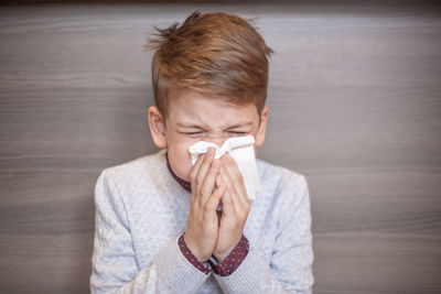 Close-up of boy blowing nose while sitting at home