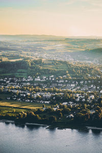 Aerial view of townscape by river against sky