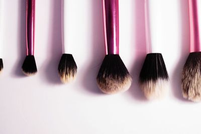 Close-up of various make-up brushes on table against white background