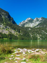 Scenic view of lake and mountains against clear blue sky