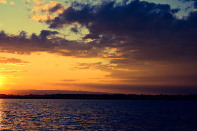 Scenic view of river against cloudy sky during sunset