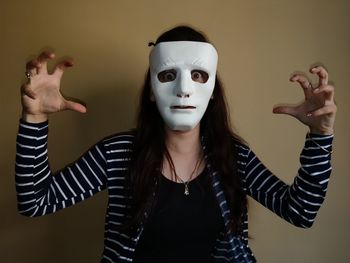 Close-up portrait of shocked woman wearing mask while gesturing against wall