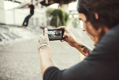 Man photographing with mobile phone on city street