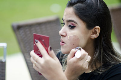 Close-up portrait of young woman holding camera