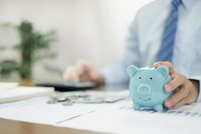 Midsection of woman holding piggy bank on table