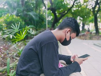 Side view of man using mobile phone outdoors