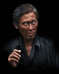 Portrait of young woman against black background