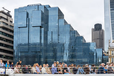 People in modern buildings against sky in city