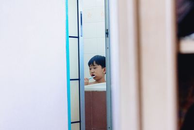 Cute boy brushing teeth in bathroom at home