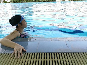 Full length of boy sitting in swimming pool