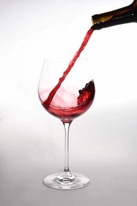 Close-up of red wine in glass against white background