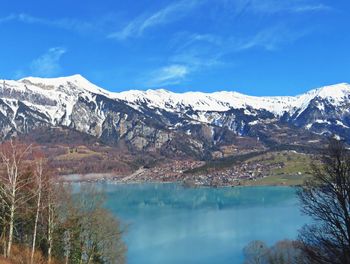 Scenic view of lake by snowcapped mountains against sky