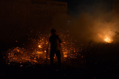 Silhouette man with fire crackers at night