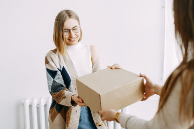 A girl receives a parcel from a courier, delivery, order, box, online shopping, millennial, hipster,