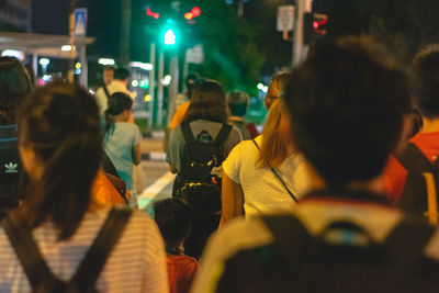 Rear view of people on street in city at night