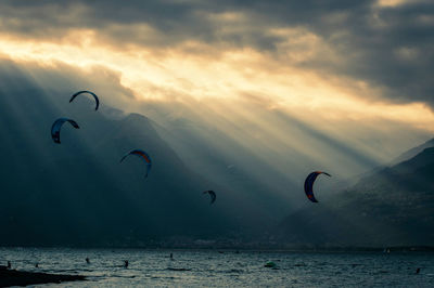 People on sea against sky during sunset