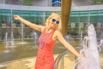Smiling woman wearing sunglasses while standing by fountain