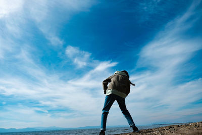 Rear view of man standing by sea against sky