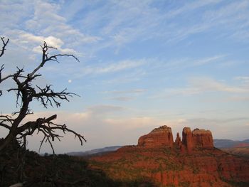 Rock formations on landscape against sky and moon