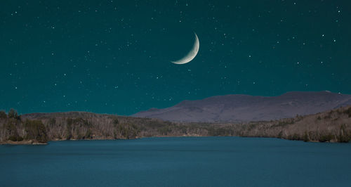 Scenic view of sea and mountains against sky at night