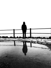 Rear view of silhouette man standing on bridge against sky