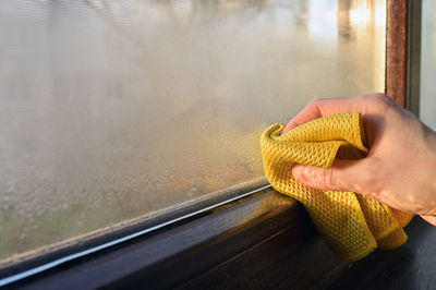 Midsection of person holding glass window