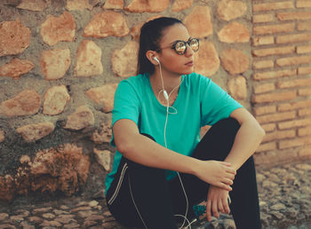 Woman listening music against wall