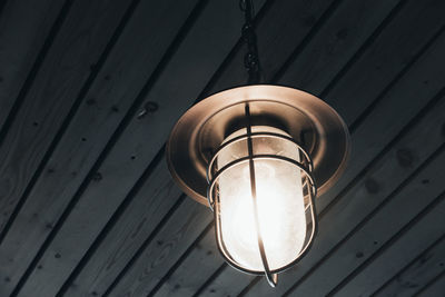 Low angle view of pendant light hanging from wooden ceiling