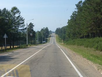 Empty road amidst trees against sky