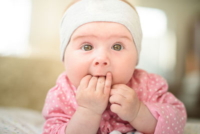 Portrait of cute baby girl lying on bed at home