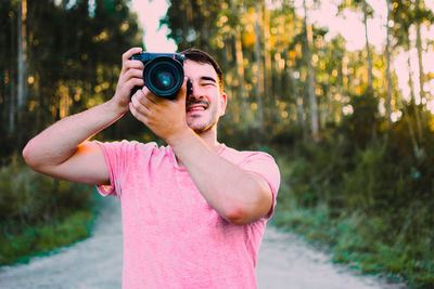 Portrait of young man taking photo with camera