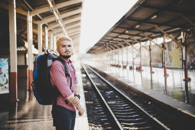 Portrait of young man standing at railroad station platform