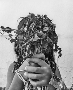 Close-up of woman holding plant against wall