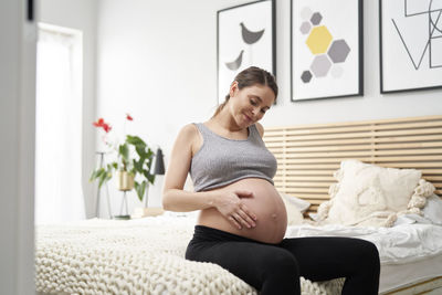 Pregnant woman sitting on bed