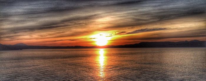 Scenic view of sea against dramatic sky during sunset