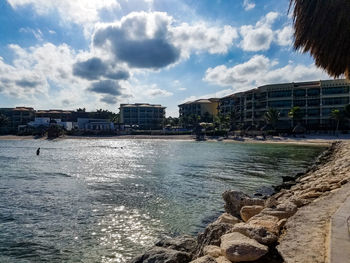 View of buildings at waterfront against cloudy sky