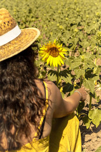 Midsection of woman sitting by sunflower