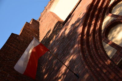 Low angle view of flag against buildings against clear blue sky