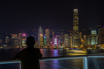 Woman standing against illuminated buildings at night