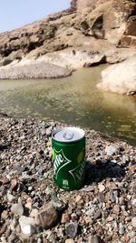 Container on rock by lake against sky