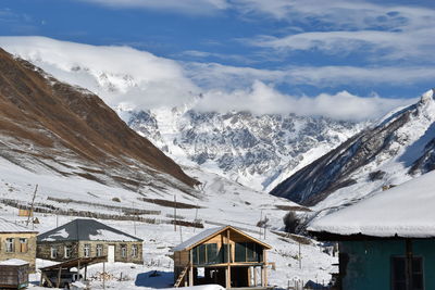 Panoramic view of buildings and snowcapped mountains against sky