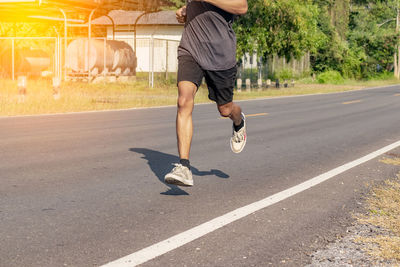 Man running with umbrella on road
