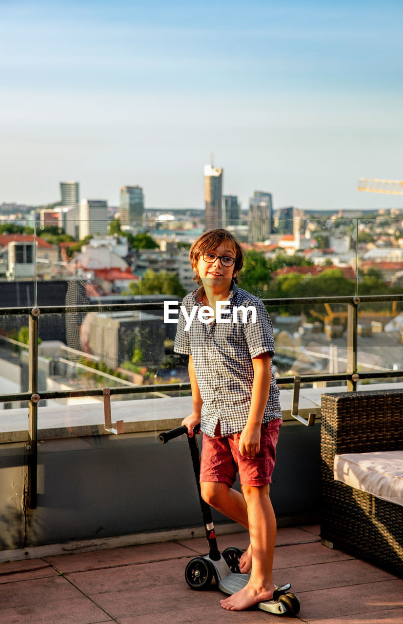 Full length of a boy standing against railing in city