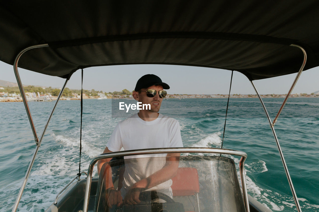 A young guy controls a boat on the sea.