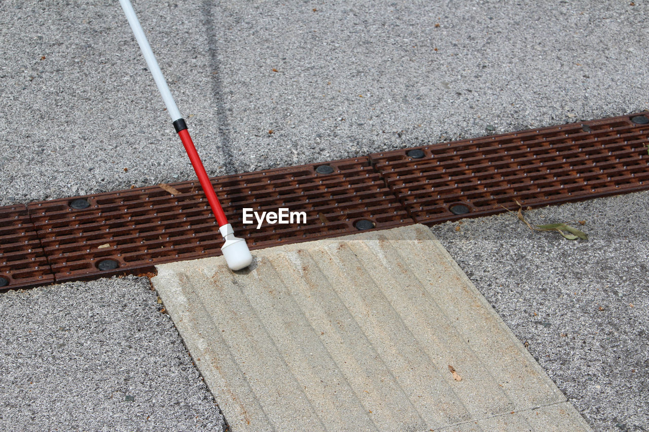 HIGH ANGLE VIEW OF METAL RAILING ON SIDEWALK BY ROAD