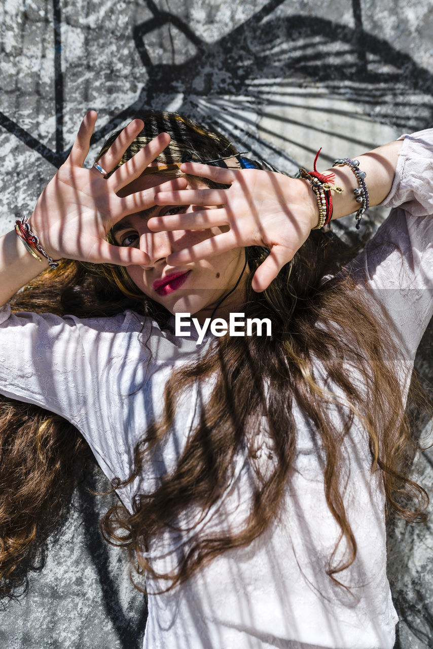 Young woman hiding face with hands while lying on concrete floor