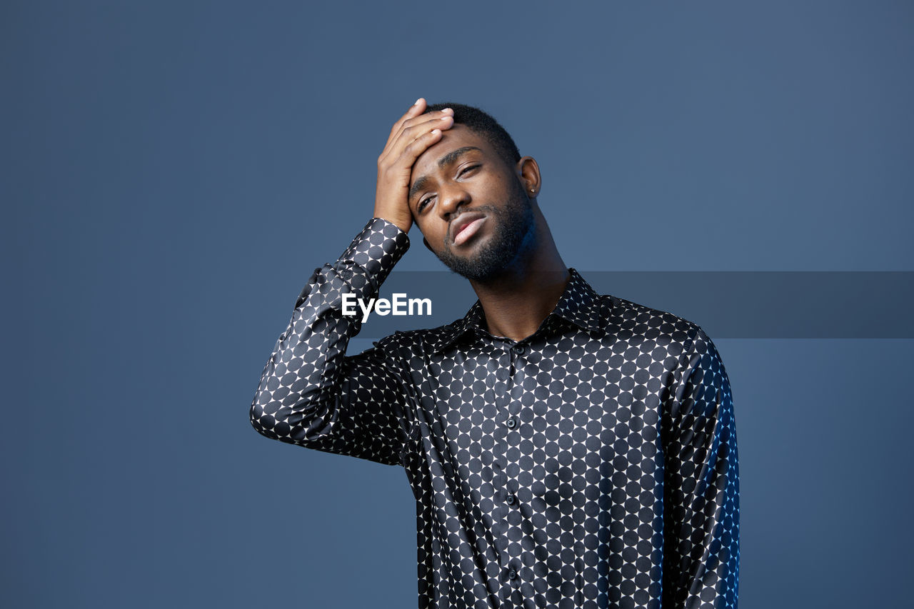low angle view of young man with arms crossed standing against black background