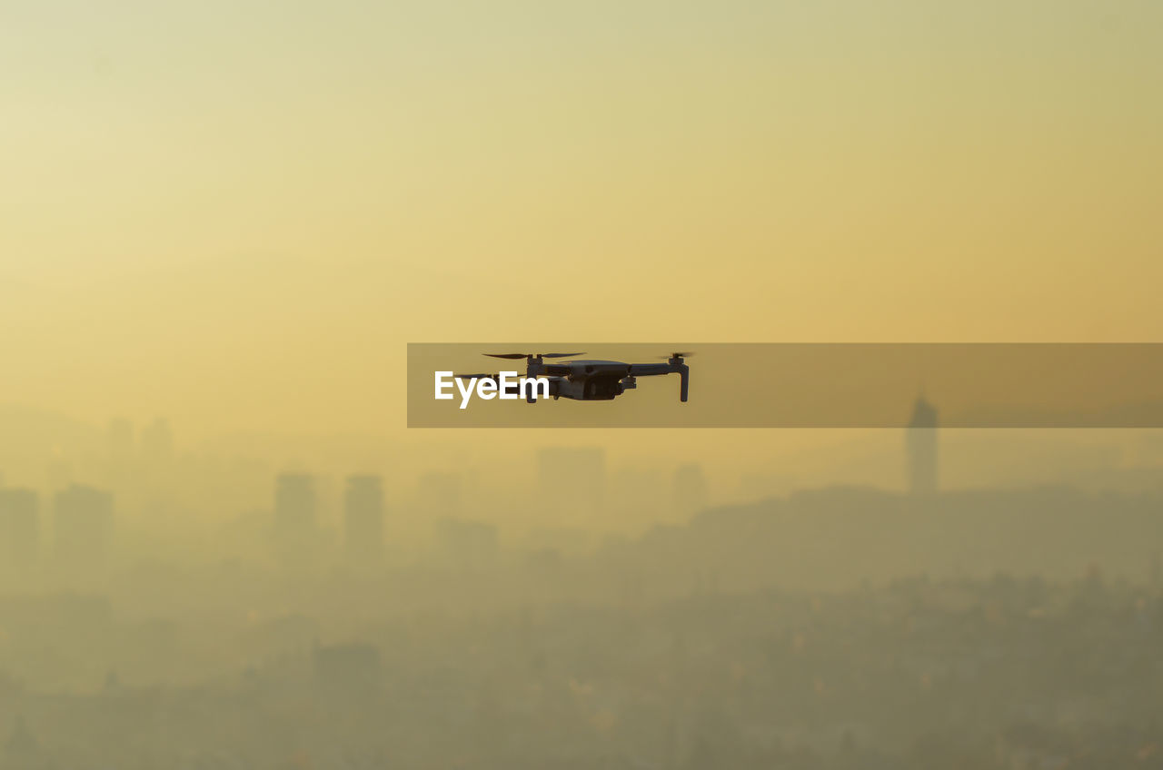 Airplane flying against sky during sunset