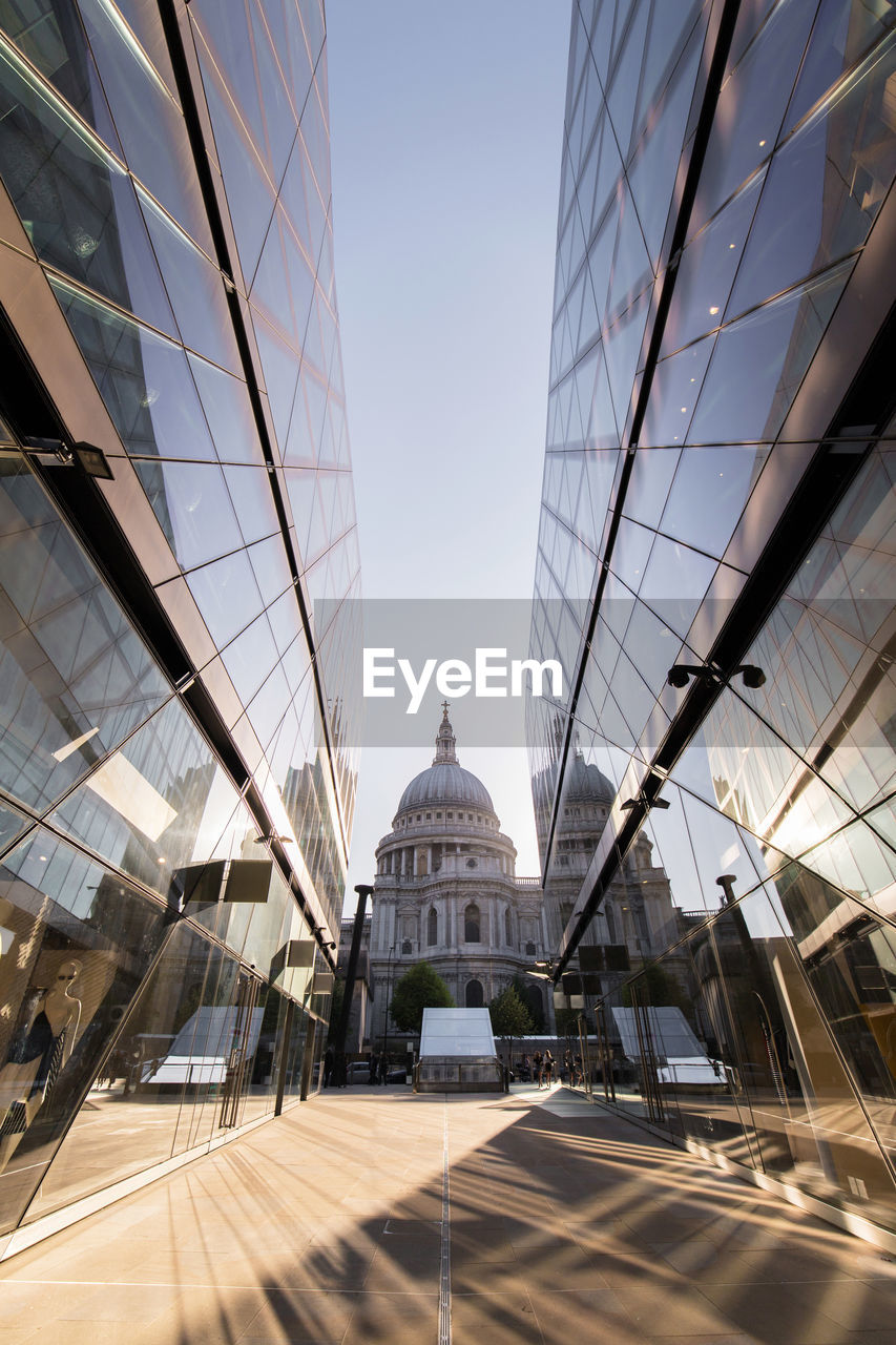 Perspective view of saint paul cathedral between shiny glass walls of futuristic skyscrapers in city of london