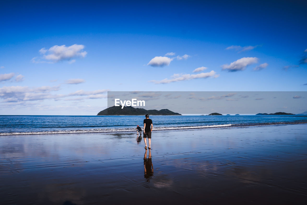 Rear view full length of teenage boy walking at beach